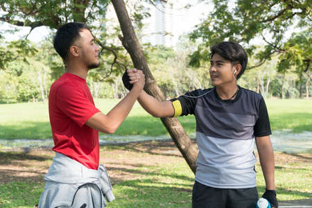 Friend of greeting the morning with holding hands after running exercise. Two man athletic friends...