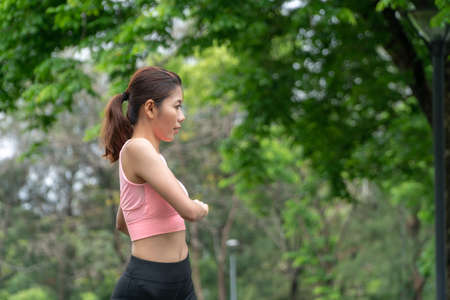 Beautiful young woman wearing orange sports warm up before exercise. Sporty young woman warming up before running in the public park. Sports and lifestyle concept.の写真素材