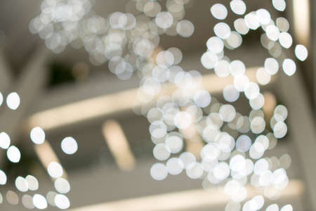Defocused bokeh blurry lights. Abstract blur of white bokeh lighting for festival and celebration. Bokeh of light in shopping malls blurred backgroundの写真素材