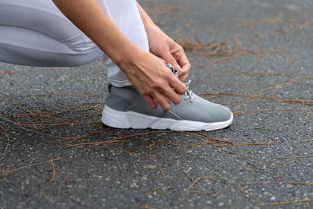 Young runner woman tying shoelaces for jogging at park focus on hands. healthy lifestyle and sport concepts.の写真素材