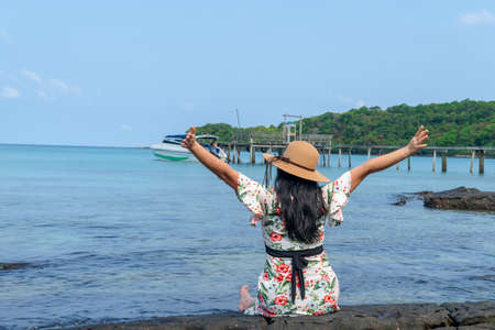 Behind woman sitting on the rock with hat in the sea for relax in holiday in the koh kood Island-Thailand. relaxing and vacation conceptの写真素材