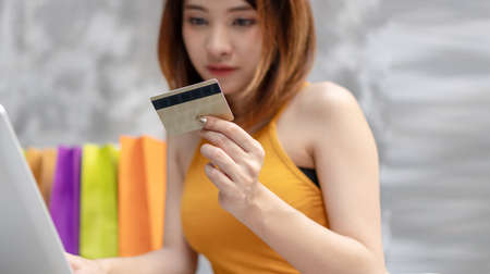 Ecommerce and Shopping online concept. Young woman holding credit card with shopping bag and...