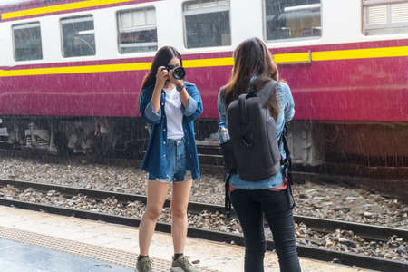 Photographer young woman taking pictures holding digital camera in station. Attractive girl travel...