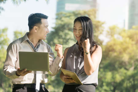 Concept success business Attractive businessman and businesswoman looking at laptop in the park....