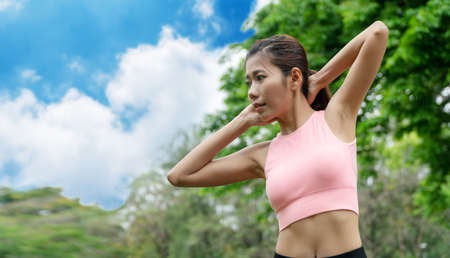 Attractive young woman wearing orange sports warm up before exercise. Sporty young woman warming up...