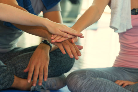 Hands of fitness people stacking hands in the gym. Group of friends with stack of hands in fitness center. Concept of teamwork and leadership.の写真素材