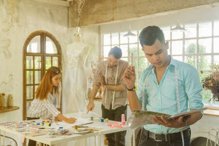 Young asian male desiner standing with desiner team working in the studio.の写真素材