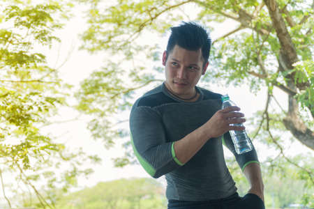 Young man holding bottle of water after exercise.