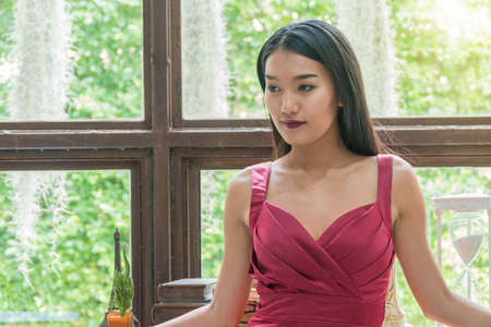 Beautiful Asian female standing wearing red dress.