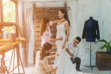 Three asian fashion designers are working to fix evening dresses for beautiful customers.