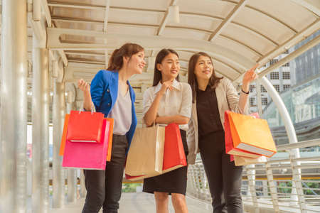 Three beautiful young woman carrying shopping bags walking outside a shopping mall.