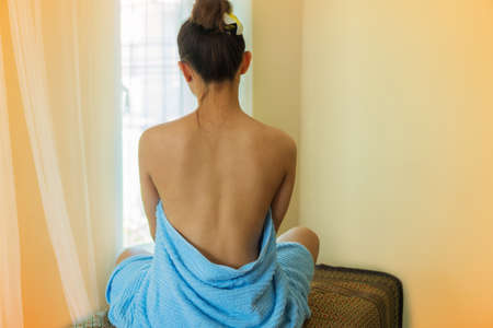 Beautiful and sexy asian young woman sitting with bare back on bed spa with blue towel.の写真素材