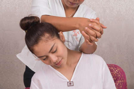 Concept thai Massage. Beautiful Asian young woman getting herbal massage thai massage in spa salon.Thai girl reflexology on shoulder with masseur.の写真素材