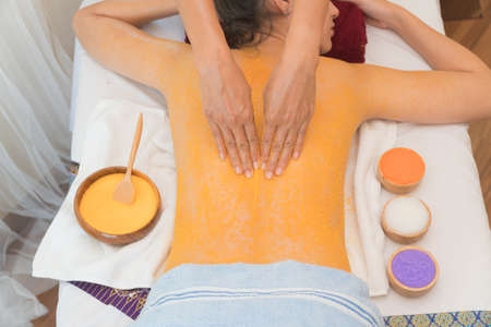 Beautiful Asian young woman receiving back salt with massage hand in spa salon. concept relaxation and health spa. Focus massage hand.の写真素材
