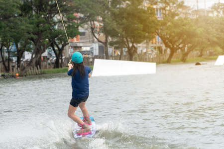 The back of the young woman wake boarding on a lake with cable in Bangkok Thailand. Concept sport and leisure activities.のeditorial素材