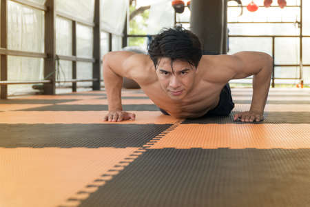 Closeup Of Healthy handsome man doing pushups during gym workout. Sporty Athletic male exercising in the gym. Sports And Fitness Conceptの写真素材