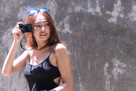 Cheerful photographer young woman with sunglasses holding camera taking photo in city. Traveler young girl use digital camera take photo reflex building while during travel. Photography concept.の写真素材