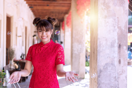 Cheerful beautiful smile young woman wear cheongsam deep pink dress holding hands looking at camera. Festivities and Celebration conceptの写真素材