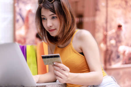 Ecommerce and Shopping online concept. Young woman holding credit card with shopping bag and purchase order using laptop computer.の写真素材