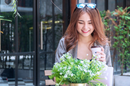 Successful business working goal concept. Cheerful smile business woman working with laptop holding cup of coffee in her hand in coffee shop cafÃ©.の写真素材