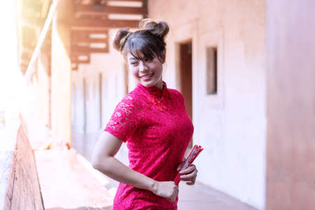Portrait beautiful young woman wear cheongsam red dress holding a fan looking at something. Festivities and Celebration conceptの写真素材