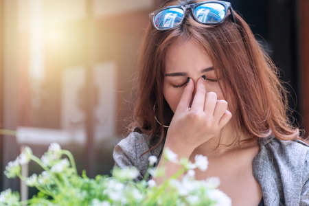 Tired young businesswoman massaging nose bridge feeling eye strain or headache trying to relieve...