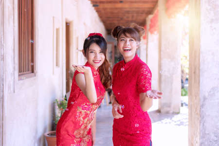 Cheerful beautiful smile two young woman friend wear cheongsam red dress holding hands looking at the soap bubble feeling fun. Festivities and Celebration conceptの写真素材
