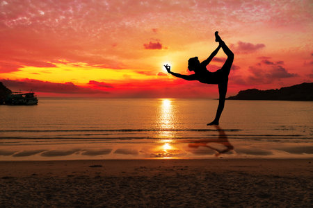 Silhouette of healthy young woman practicing yoga on tropical beach with sky sunset. People doing yoga standing on the Island. Healthy and lifestyle concept.の写真素材