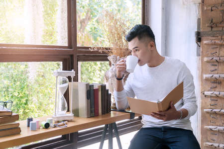 Attractive cheerful young handsome man wearing glasses with hand holding white cup of coffee and...