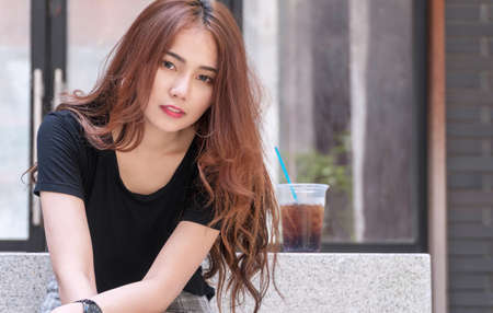 Cheerful young woman with cup of sparkling water ice with copy space. Happy girl brown long hair...