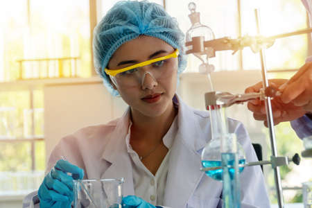 Researchers finding ways to protect and preserve the health of the people have good healthy in a modern laboratory. Young woman scientist working with protective eyeglasses in laboratory. Double exposure style.の写真素材