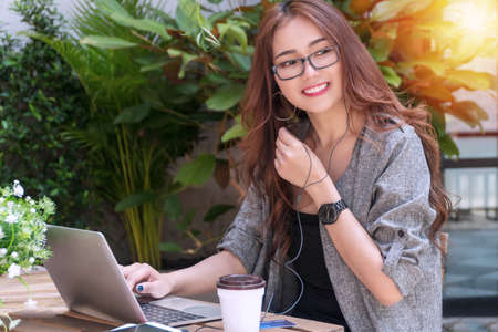 Business young women with glasses sitting in garden talk through smartphones using laptop online...