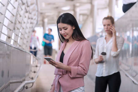 Charming young woman looking at smartphone in her hands. Businesswoman use cellphone search...