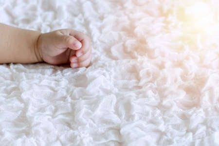 Hand of innocence little baby boy lying on the white bed with copy space. Arm of newborn sleeping in the room.の写真素材