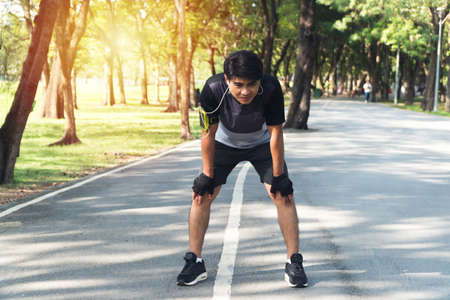 Men tired after jogging in the Park. Tired runner man breathing taking run break in the park having...