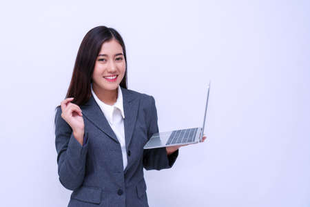 Professional businesswoman holding laptop in her hand while looking at camera on isolated white...