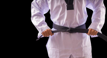 Taekwondo traditional man hand hold black-belt on black background for advertising. The karate man standing with black belt isolated on black with copy space.の写真素材