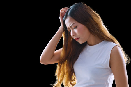 Tired young woman get stress on isolated black background. Portrait lady long brown hair touch her temples feel stress and headache.の写真素材