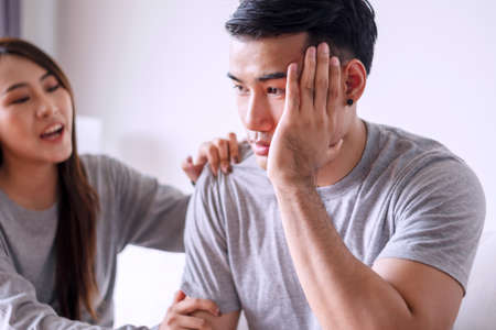 Unhappy young man have problems being quarrel with his wife sitting on sofa together at living room. Husband has attitude annoyed wife complained he very much. Couple problems in relationship concept.の写真素材