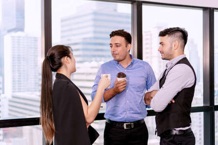 Group businesspeople standing and talking about work together on break relax time after hard work. Teamwork colleagues discuss work in coffee break at workplace office.の写真素材