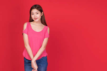 Friendly young womanl smile while standing and looking at camera over isolated red background.