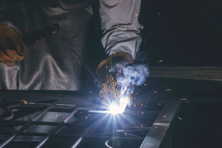 Hand of man wear glove working with arc welding machine to weld steel at outdoor. The welder welds...