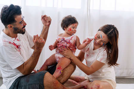Joyful family rest playful funny at home. Enjoyment daughter playing color and holding hand color...