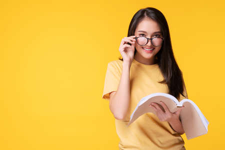 Lovely young woman look tricky taking off funny eye glasses while reading book in her hand over...