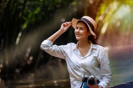 Adventure and vacation travel concept. Traveler young woman wearing hat and holding camera in her...