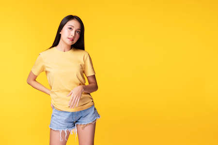 Lifestyle relax concept. Positive smile asian woman wear casual clothing while standing arms crossed over isolated against yellow background.の写真素材