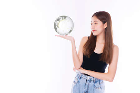 Student young girl holding small global while standing over isolated white background. Happiness woman looking at earth in own hands symbol for in the future. Lifestyle concept.の写真素材