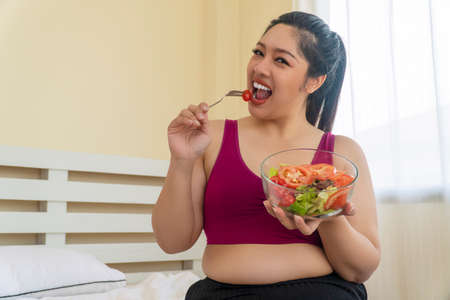 Concept food good healthy for weight loss. Smile obesity plus size women eat fresh tomato while...