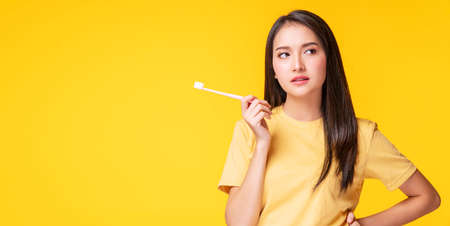 Health care dentist oral concept. Unhappy young woman serious toothache holding toothbrush in her hand while standing over isolated blue background.の写真素材