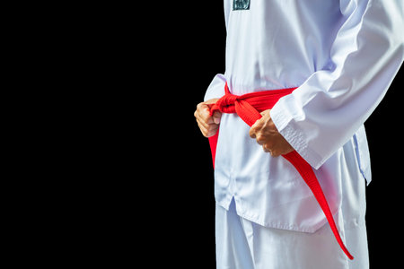 Taekwondo traditional man hand hold red-belt on black background for advertising. The karate man standing with red belt isolated on black with copy space.の写真素材